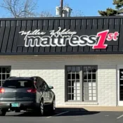 Storefront of Mattress 1st with parked car.
